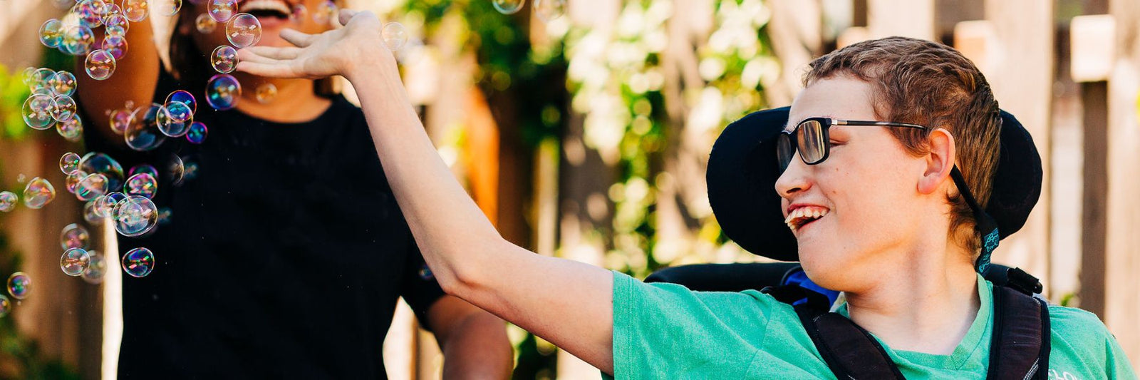 An inclusion employee and a young man with an intellectual disability blowing bubbles