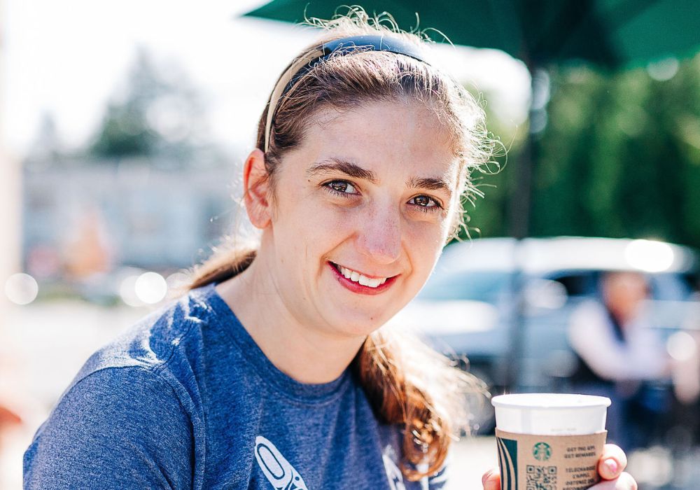 A young self-advocate drinking a Starbuck's coffee