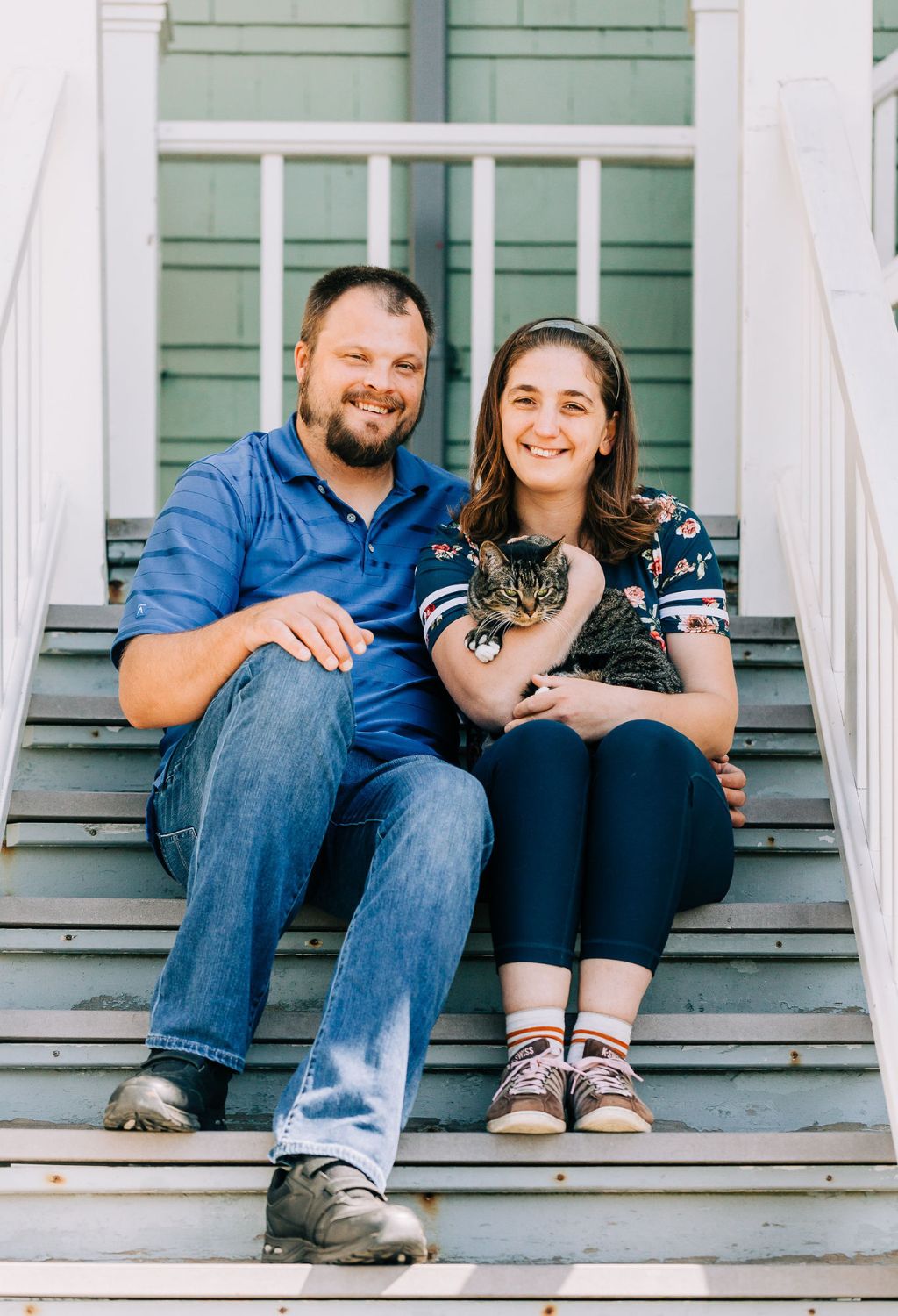 Two self-advocates sitting on stairs, snuggling a cat