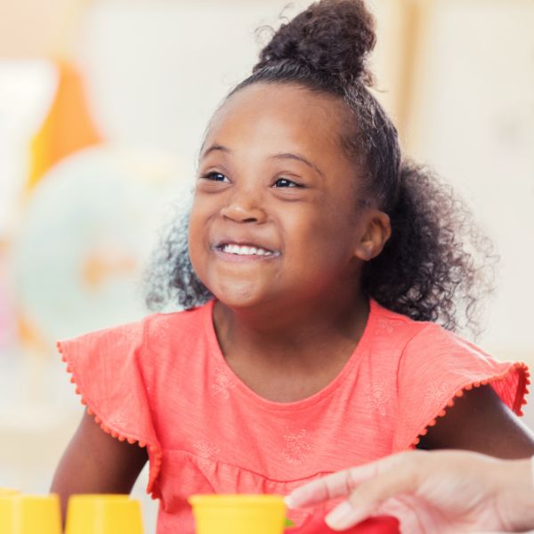 A young girl with an intellectual disability playing with yellow blocks