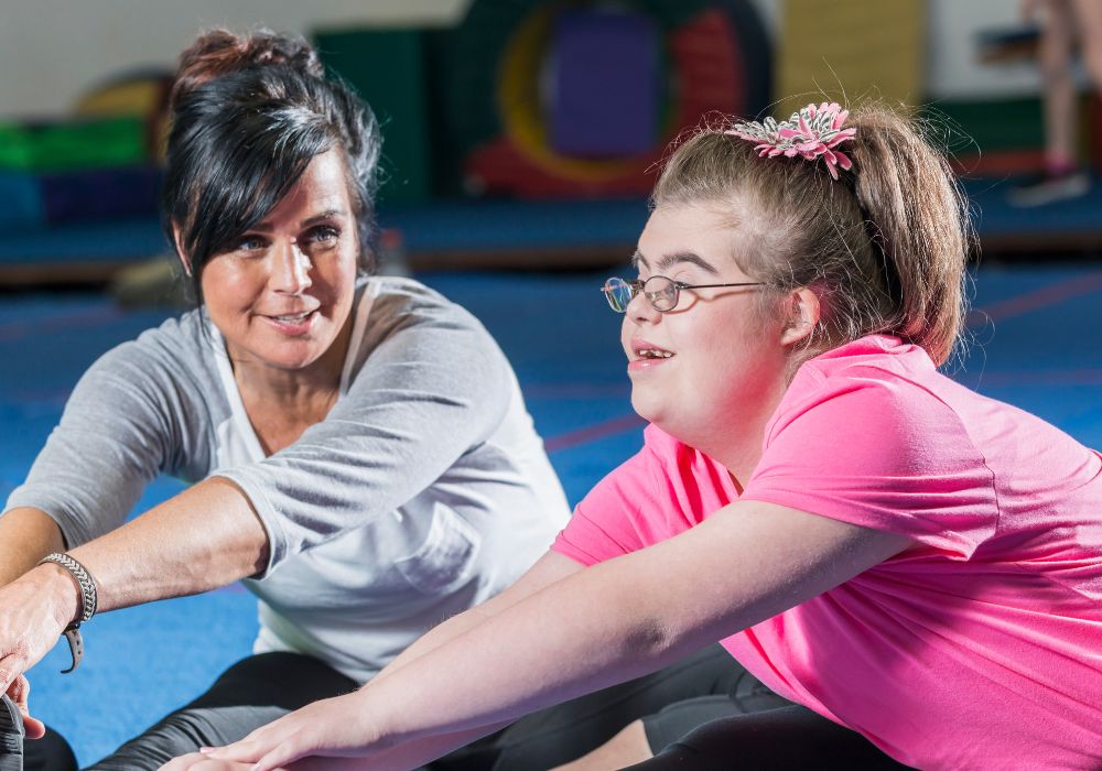 A young woman with Down Syndrome doing yoga next to the instructor