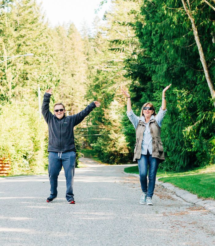 Image of an inclusion employee walking with an individual, waving their hands in the air.