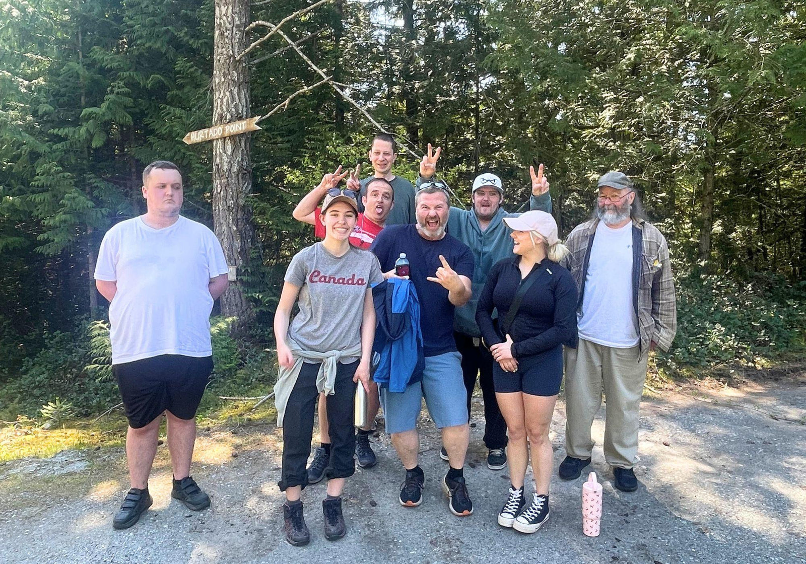 A group of people acting goofy at the trailhead after a group hike.