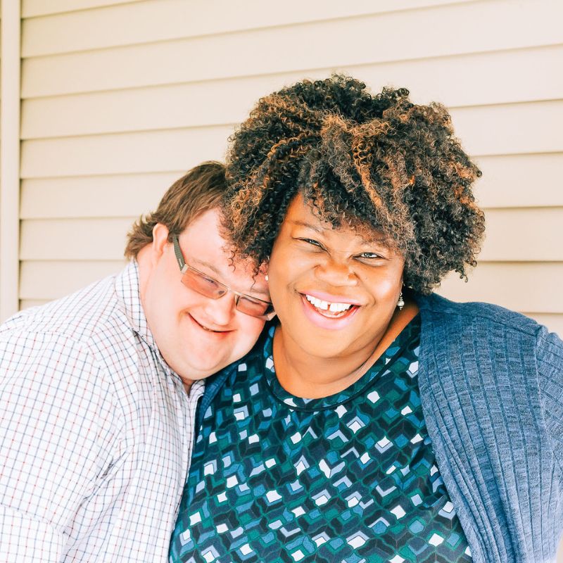 A HomeShare Provider and young man with Down Syndrome embracing