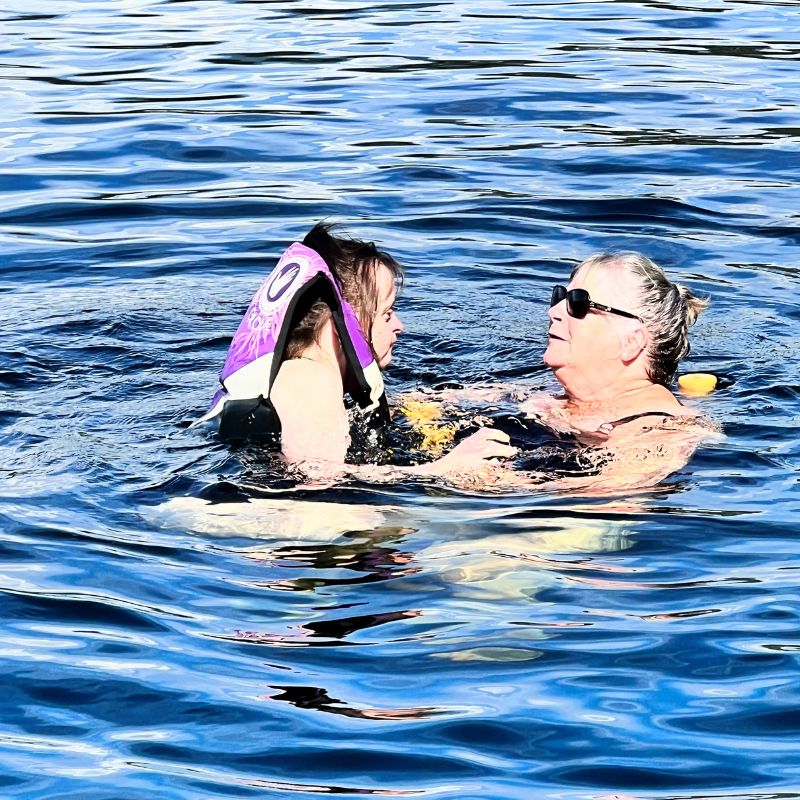 A woman and individual with an intellectual disability swimming in the lake
