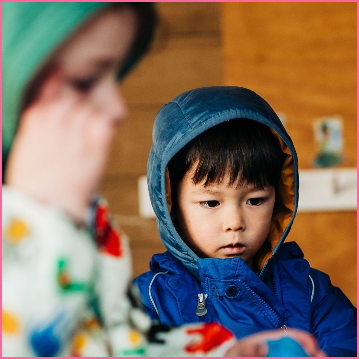 Image of a young boy in a blue jacket looking intently at something.