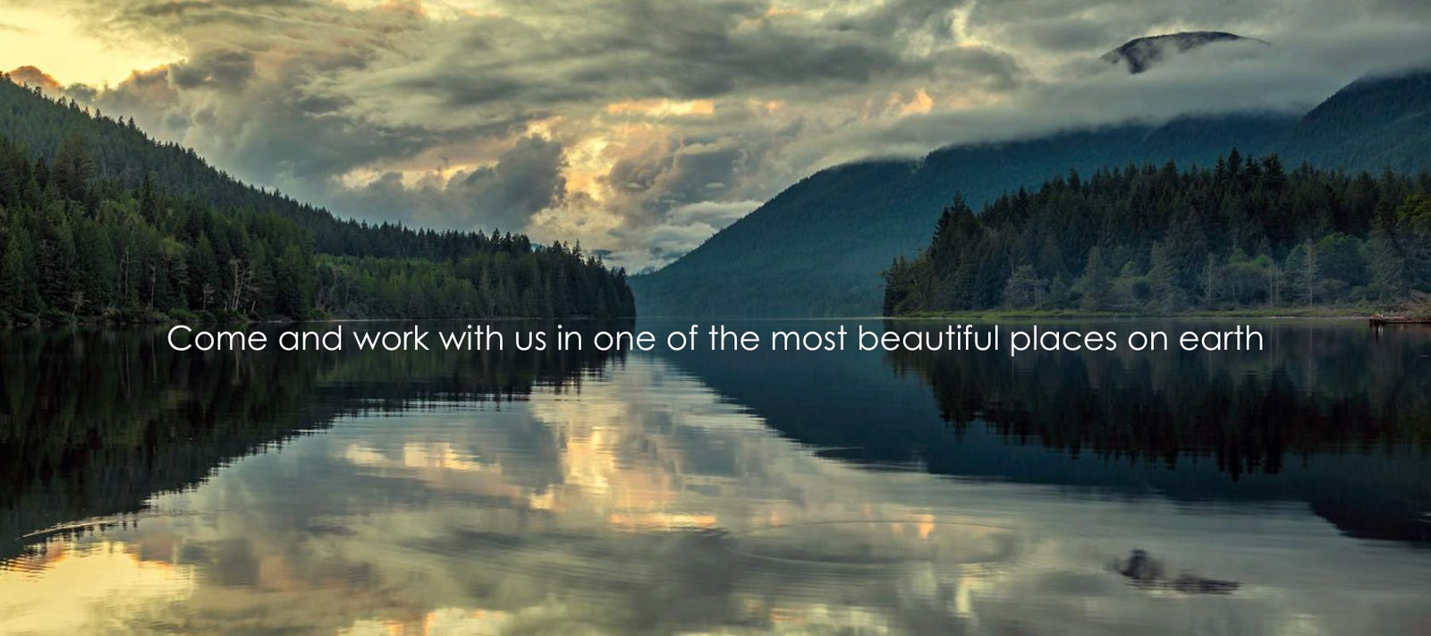 Photo of a lake in qathet with the mountains and trees reflecting on the calm water