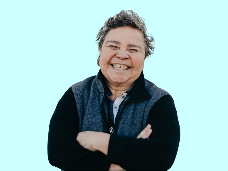An older woman standing with her arms crossed with a big smile on her face - inclusion powell river