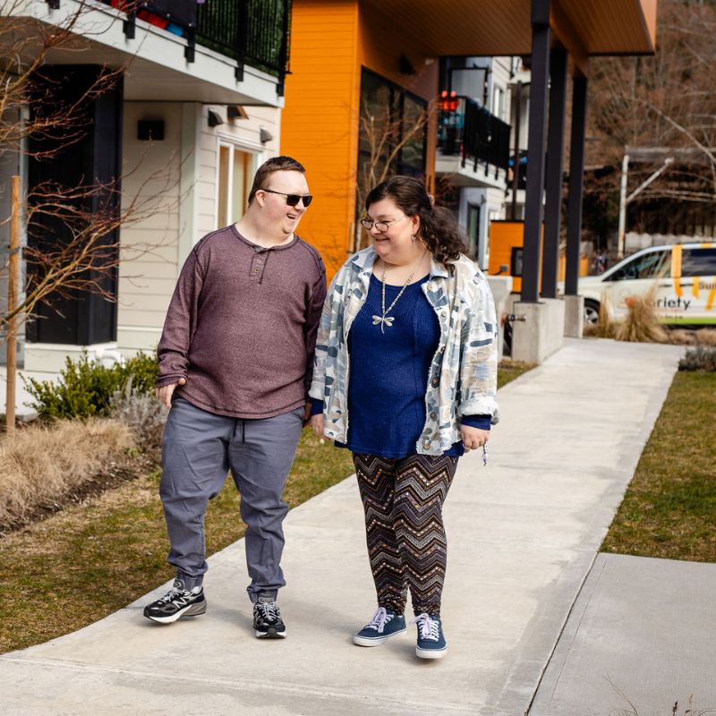 Two individuals with an intellectual disability walking down the street together. 