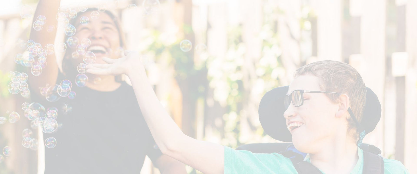 An inclusion employee and an individual with an intellectual disability blowing bubbles