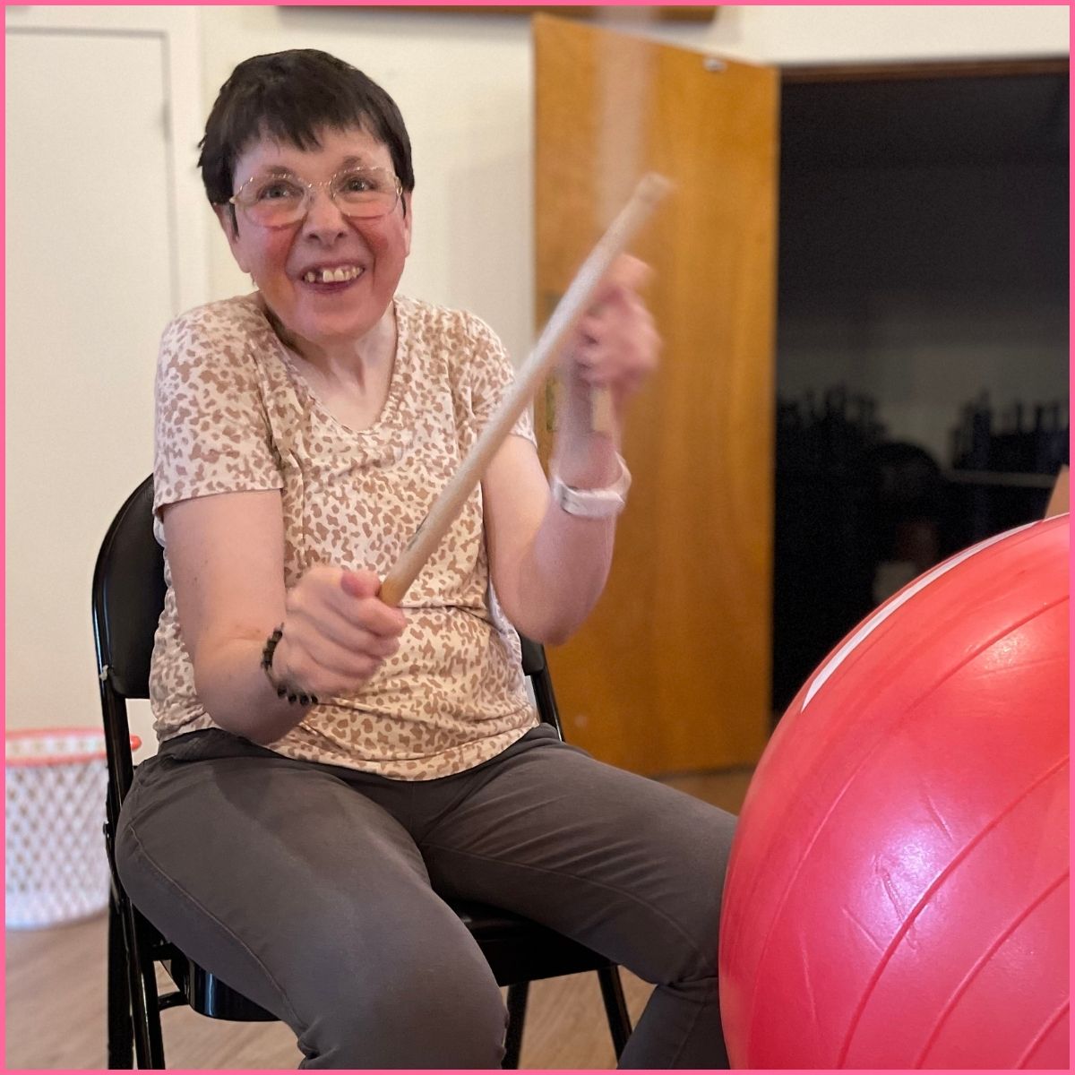 A woman playing drums on an exercise ball. 
